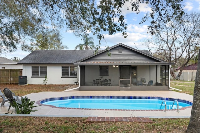 rear view of property with a fenced in pool, fence, a sunroom, and central air condition unit