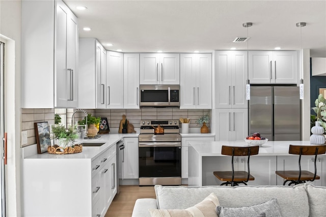 kitchen featuring light countertops, appliances with stainless steel finishes, a sink, and tasteful backsplash