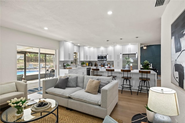 living area featuring light wood-style flooring, visible vents, and recessed lighting