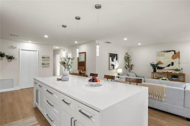 kitchen with light wood-style floors, white cabinetry, and visible vents