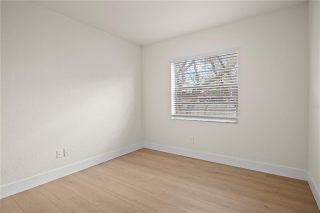 unfurnished room with light wood-type flooring and baseboards