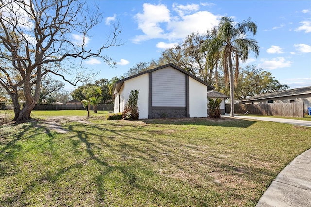 view of home's exterior with stone siding, fence, a lawn, and stucco siding