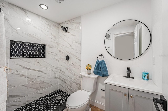 bathroom with toilet, vanity, and tiled shower