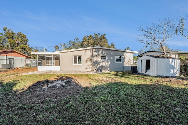 back of property with a shed, a lawn, central AC unit, and a sunroom