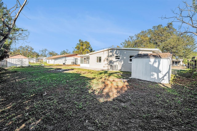 back of property with a storage unit and a yard