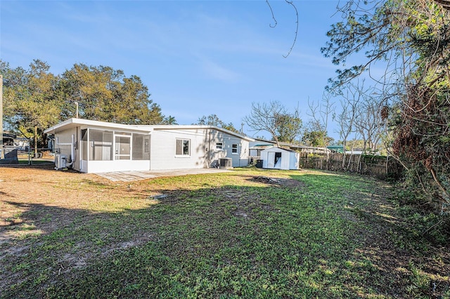 rear view of property featuring a yard, a sunroom, and a storage shed