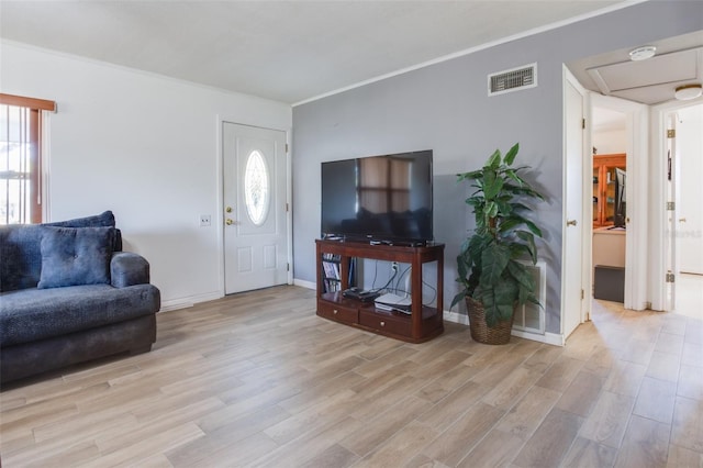 living area featuring baseboards, light wood-type flooring, visible vents, and crown molding