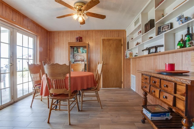 dining area with a wealth of natural light, visible vents, wood walls, and wood finished floors