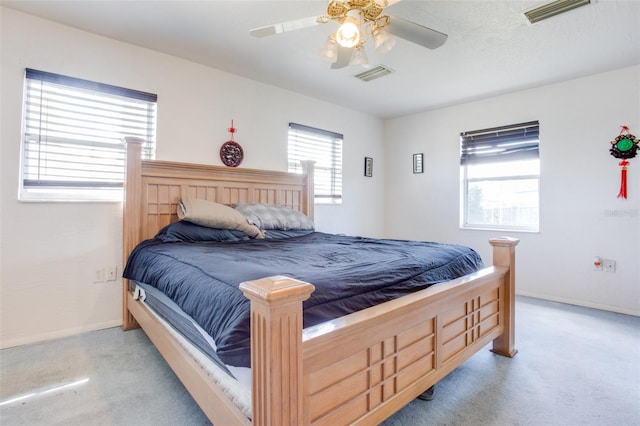 bedroom with a ceiling fan, light colored carpet, visible vents, and baseboards