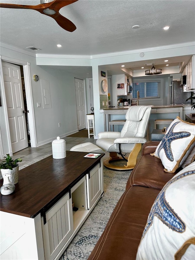 interior space featuring baseboards, visible vents, a ceiling fan, a textured ceiling, and recessed lighting