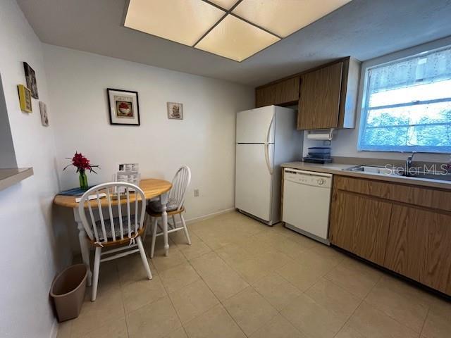 9815 47th Ave N Unit 303, Saint Petersburg, FL 33708 - kitchen with baseboards, a sink, white appliances, and light countertops