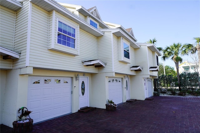 townhome / multi-family property featuring driveway, an attached garage, and stucco siding