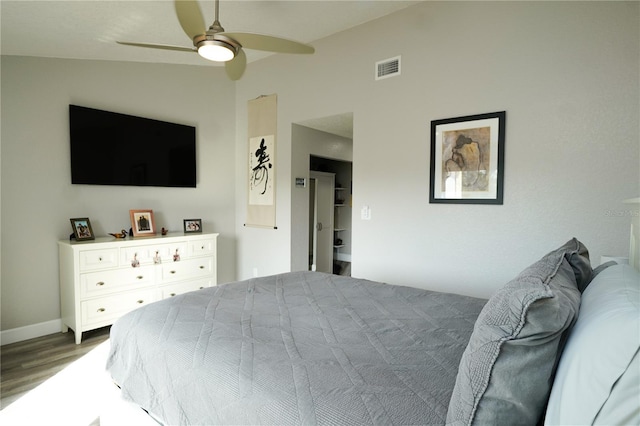 bedroom with a ceiling fan, visible vents, vaulted ceiling, and wood finished floors