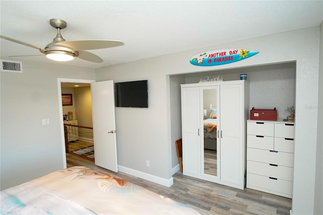 bedroom featuring baseboards, visible vents, ceiling fan, and light wood finished floors