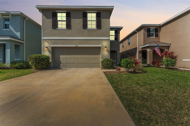 view of front of house featuring a garage, a front yard, concrete driveway, and stucco siding