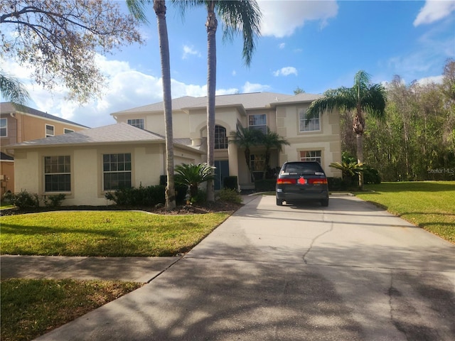 view of front of house with a garage, a front yard, concrete driveway, and stucco siding