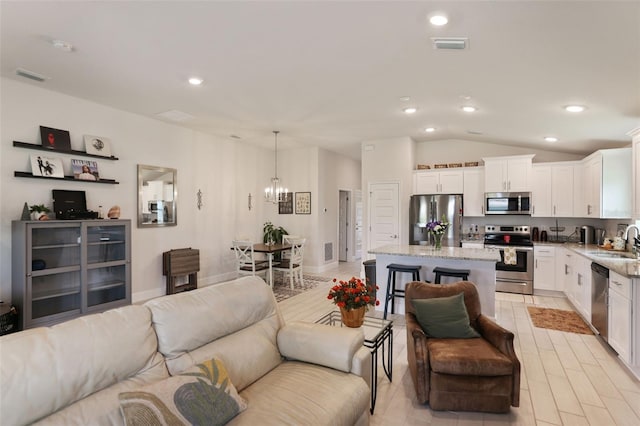 living area featuring an inviting chandelier, recessed lighting, visible vents, and vaulted ceiling