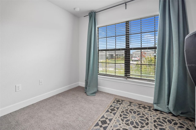 spare room with baseboards and carpet floors