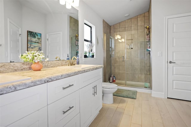 bathroom featuring wood finished floors, double vanity, a sink, a shower stall, and vaulted ceiling