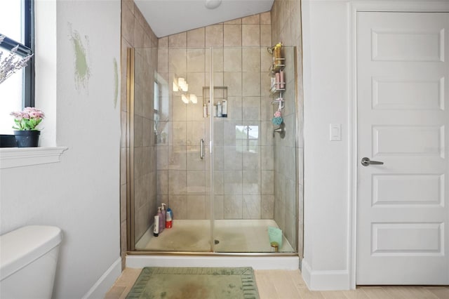 bathroom featuring a shower stall, toilet, and baseboards