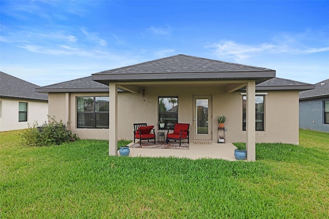 back of property featuring a shingled roof, a patio area, a lawn, and stucco siding