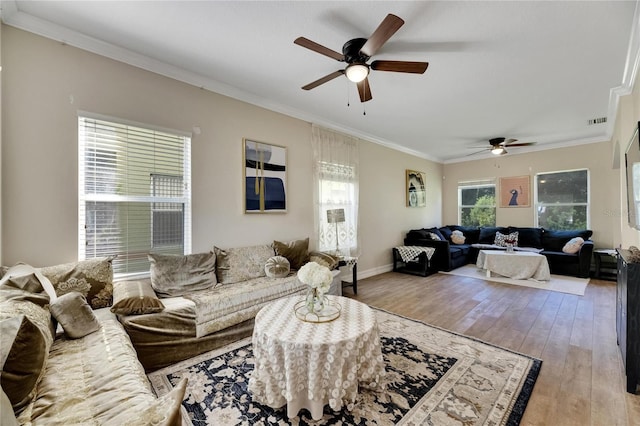 living room featuring ornamental molding, visible vents, light wood-style flooring, and baseboards