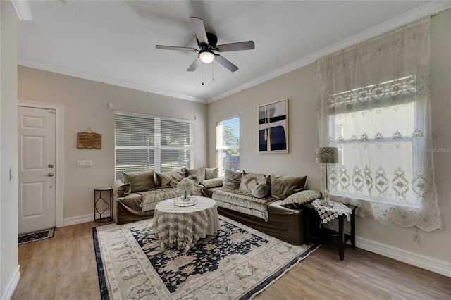 living area with ceiling fan, ornamental molding, light wood-type flooring, and baseboards