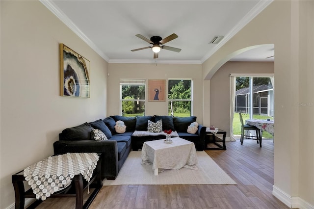 living area featuring a wealth of natural light, light wood-style flooring, visible vents, and crown molding