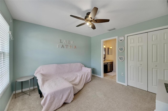 bedroom featuring light carpet, a closet, connected bathroom, and baseboards