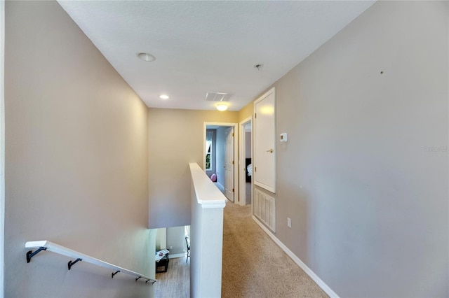 hall featuring light colored carpet, baseboards, visible vents, and an upstairs landing