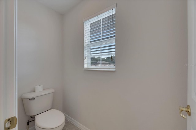 half bathroom with toilet and baseboards