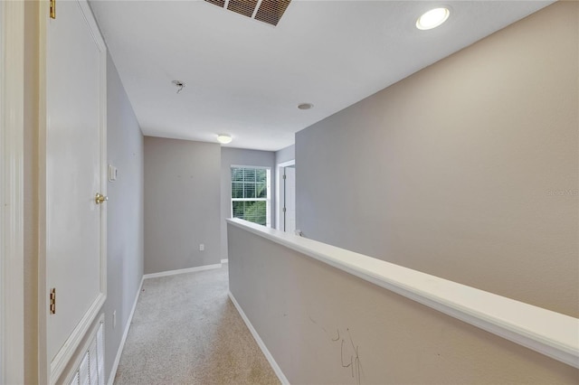 corridor with an upstairs landing, light colored carpet, visible vents, and baseboards