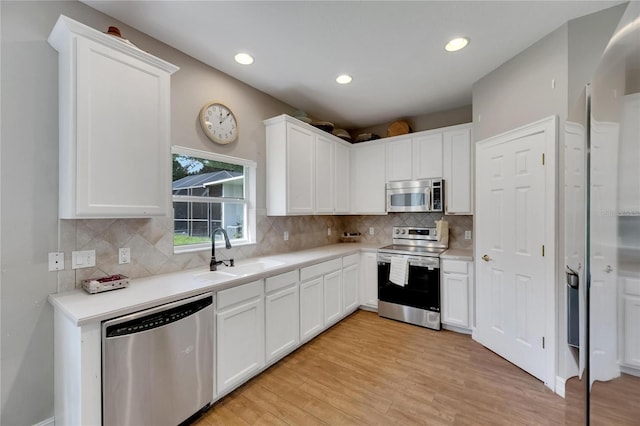 kitchen with white cabinets, appliances with stainless steel finishes, light countertops, and a sink