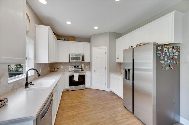 kitchen featuring white cabinets, appliances with stainless steel finishes, light countertops, and a sink