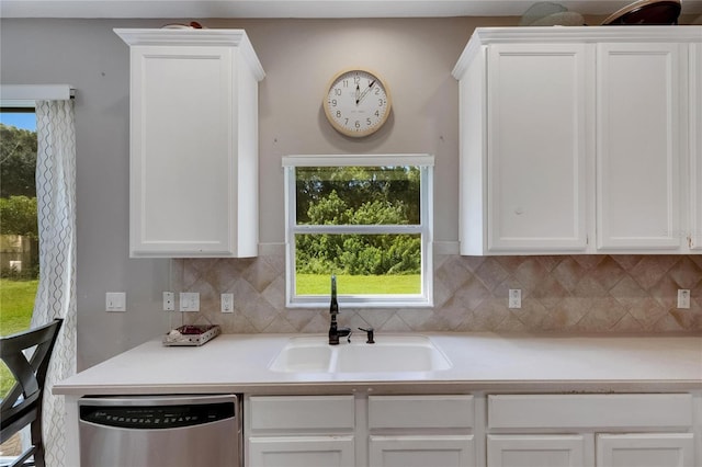 kitchen with light countertops, stainless steel dishwasher, a sink, and white cabinetry