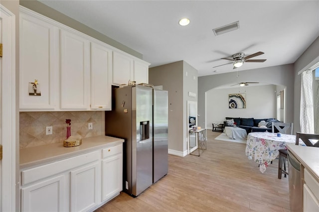 kitchen featuring appliances with stainless steel finishes, arched walkways, white cabinets, and light countertops