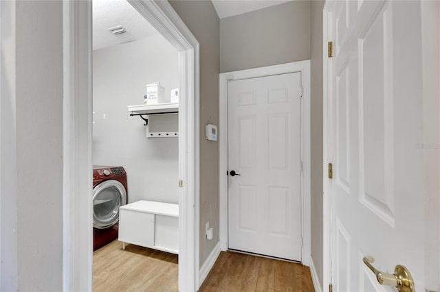 interior space featuring washer / dryer, visible vents, light wood-style floors, and baseboards