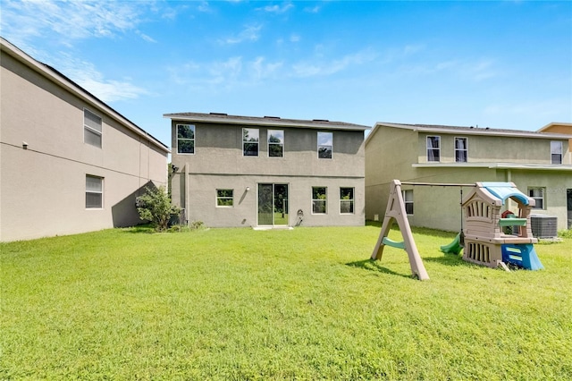 back of house featuring a lawn, a playground, cooling unit, and stucco siding