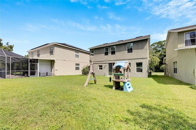 back of property with central AC, a lawn, a playground, and stucco siding