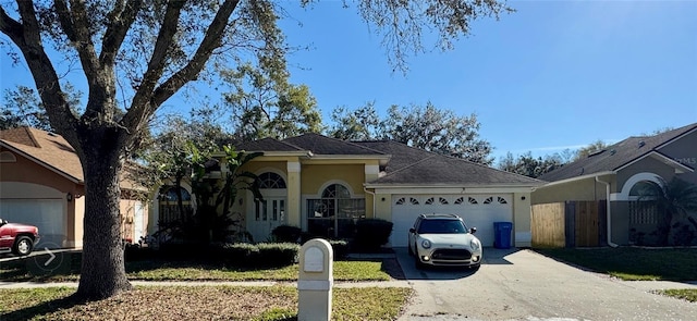 single story home with driveway, fence, an attached garage, and stucco siding