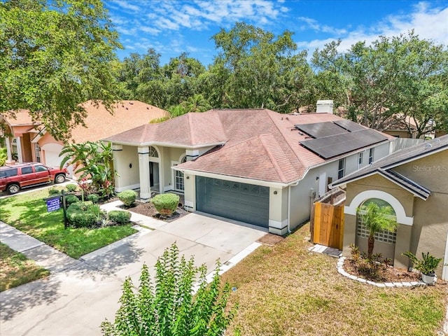 3616 Cypress Meadows Rd, Tampa, FL 33624 - mediterranean / spanish home with an attached garage, stucco siding, a front yard, roof mounted solar panels, and concrete driveway