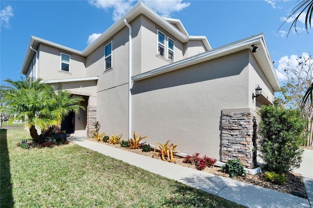 view of home's exterior featuring a yard, stone siding, and stucco siding