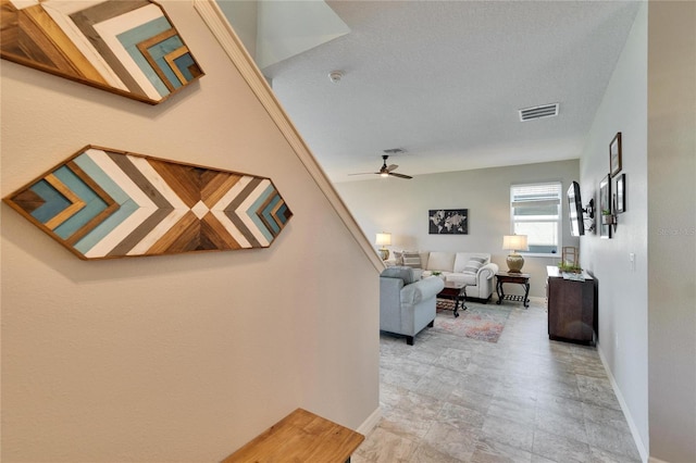 living room with a ceiling fan, visible vents, and baseboards