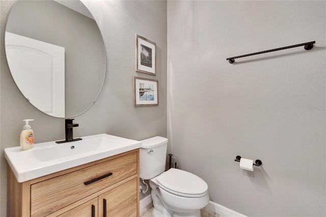 half bath featuring toilet, vanity, and baseboards