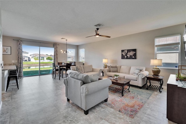 living room featuring visible vents, a textured ceiling, and ceiling fan with notable chandelier