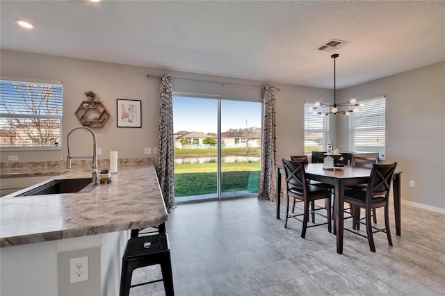 dining space with a chandelier, a textured ceiling, visible vents, and baseboards