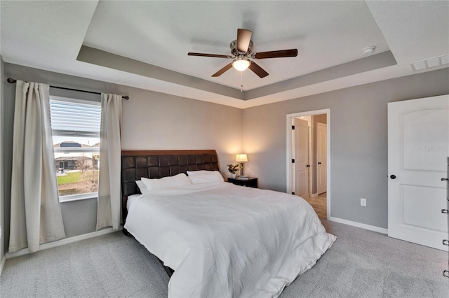 bedroom with light colored carpet, visible vents, a ceiling fan, baseboards, and a raised ceiling