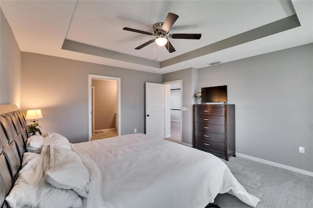 bedroom with visible vents, a tray ceiling, light colored carpet, and baseboards