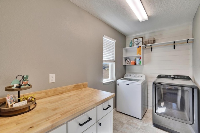 clothes washing area with cabinet space, separate washer and dryer, and a textured ceiling