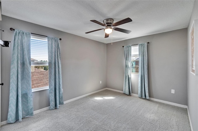 unfurnished room featuring a ceiling fan, light colored carpet, a textured ceiling, and baseboards